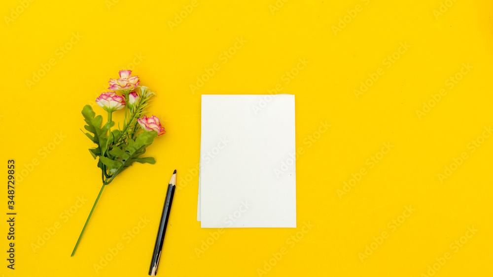flower and paper with pencil top view on yellow background minimalistic concept flower and paper with pencil top view on yellow background minimalistic concept