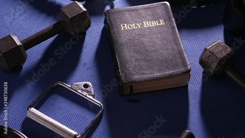 Bible Surrounded by Various Gym Equipment 