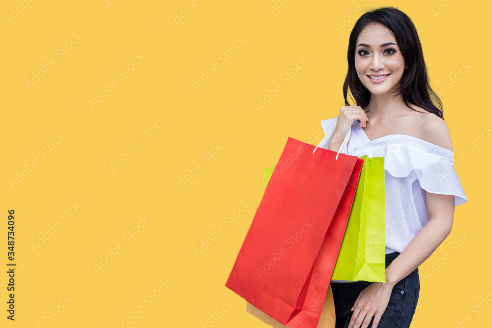 Beautiful asian young woman with shopping bags with smile while standing at the clothing store. Happiness, consumerism, sale and people concept.