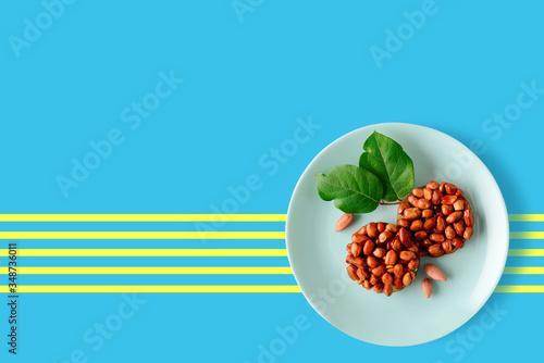 Tasty eastern sweets kozinaki made from peanuts and honey on a plate on a blue background.