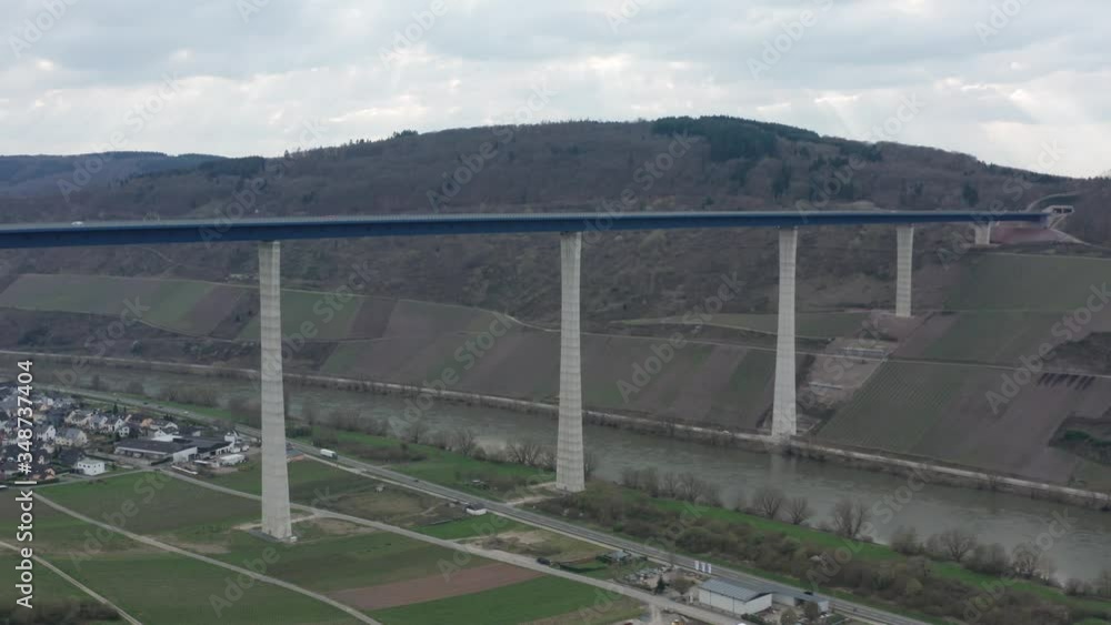 Hochmoselbrücke High Moselle Bridge in Rhineland-Palatinate Germany with cars and trucks on a freeway highway cinematic panorama rising aerial drone shot on a sunny cloudy day 25p Hochmoselbrücke High Moselle Bridge in Rhineland-Palatinate Germany with cars and trucks on a freeway highway cinematic panorama rising aerial drone shot on a sunny cloudy day 25p