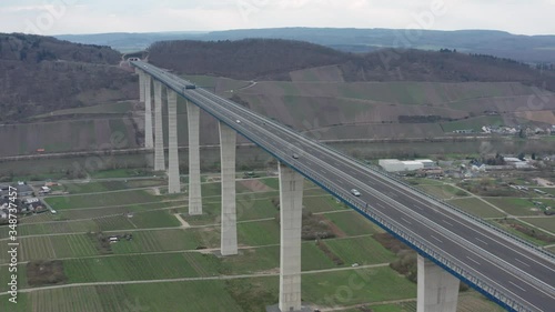 Hochmoselbrücke High Moselle Bridge in Rhineland-Palatinate Germany with cars and trucks on a freeway highway cinematic  medium aerial drone shot on a sunny cloudy day 25p photo