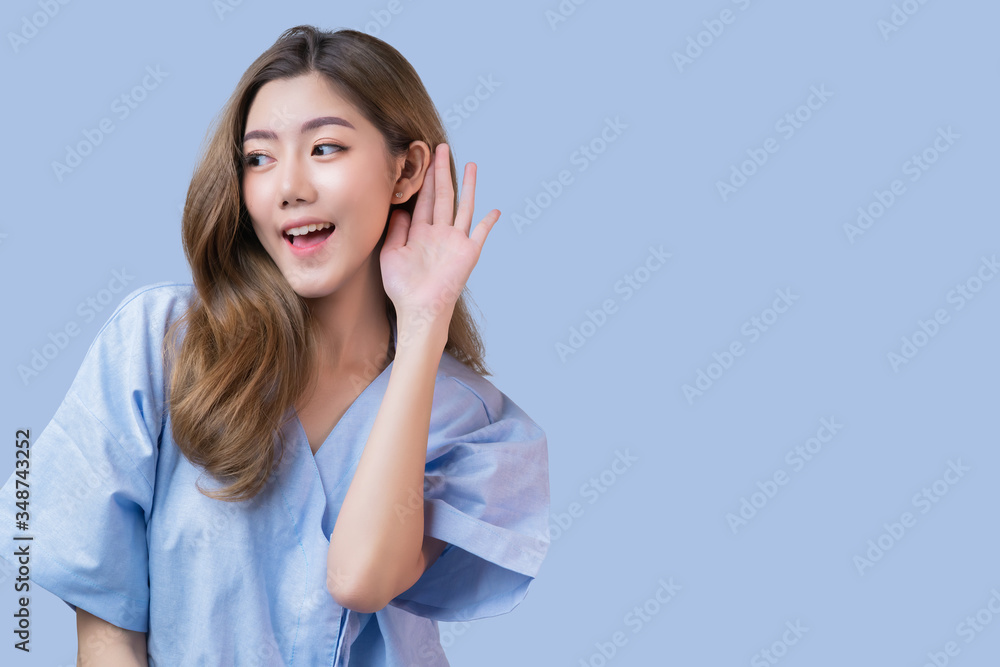 Goodnews gossip atttractive long hair asian female patient in hospital clinic uniform hand hold for help hearing happy message from somewhere isolate blue color background Goodnews gossip atttractive long hair asian female patient in hospital clinic uniform hand hold for help hearing happy message from somewhere isolate blue color background