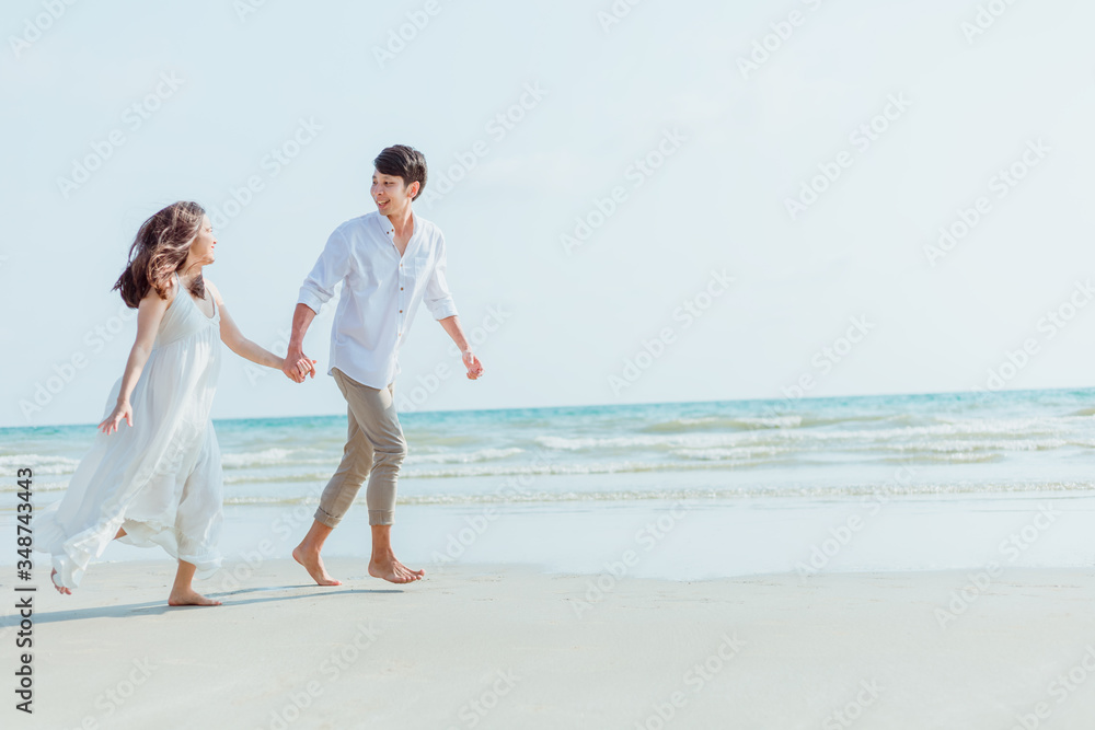 Romantic couple holding hands running and walking on beach. Man and woman in love.