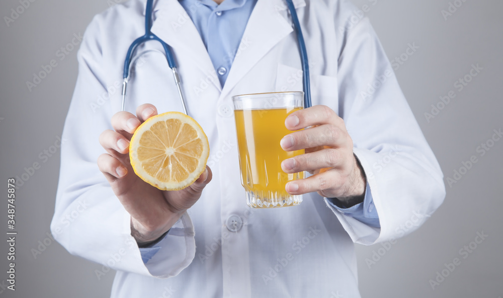 Caucasian doctor holding lemon and glass of juice. Healthy diet Caucasian doctor holding lemon and glass of juice. Healthy diet