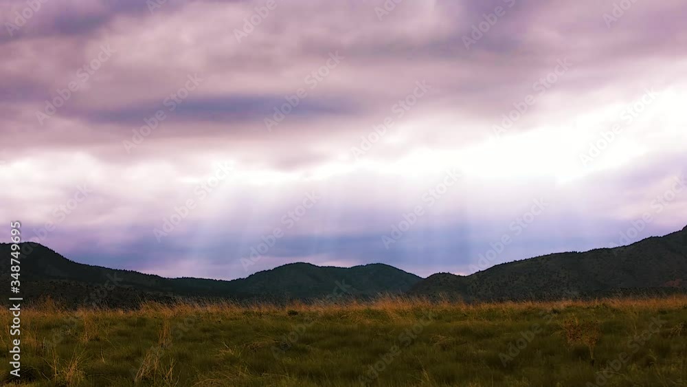 Sun rays over the rocky mountains, Colorado, with green prairie in the foreground