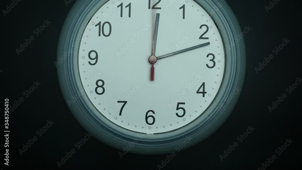 Close up Angle camera from bottom to top, White wall clock isolated 12.00 am or pm. on black background, Time lapse 60 minutes moving fast, Time concept. Close up Angle camera from bottom to top, White wall clock isolated 12.00 am or pm. on black background, Time lapse 60 minutes moving fast, Time concept.