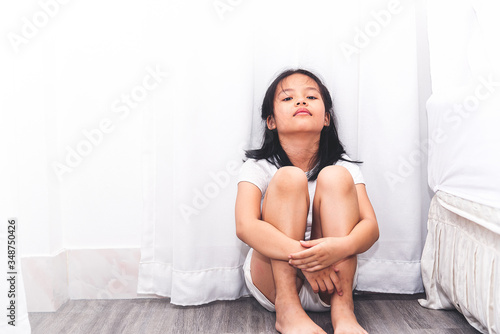 Neglected lonely child against the white wall. Little girl crying in the corner. Violence concept.