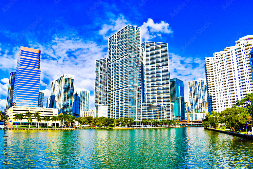 Obraz premium Brickell point and brickell key view with biscayne bay at downtown Miami Florida, blue sky, palm trees, art deco buildings reflecting on turquoise water, skyline by sunny day, financial district