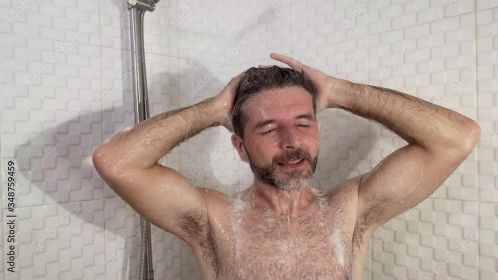 young attractive and happy man with beard taking a shower at home washing his hair with shampoo cheerful enjoying the morning shower in wellness and hygiene concept young attractive and happy man with beard taking a shower at home washing his hair with shampoo cheerful enjoying the morning shower in wellness and hygiene concept