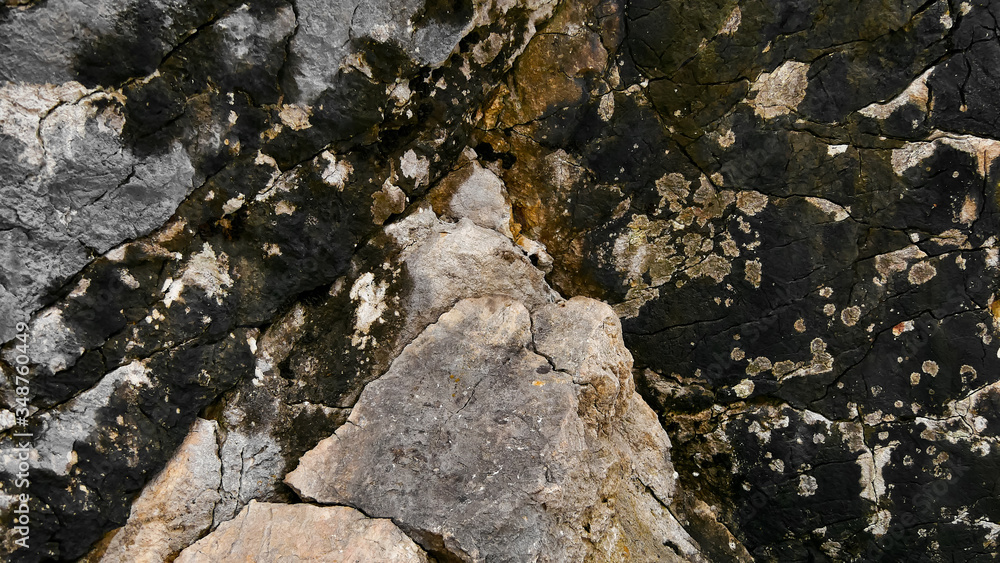 The texture of the mountains. Igneous rocks closeup of a fragment of rock with cracks, streaks. The rough surface of a stone that had been lying on the street for a long time. 