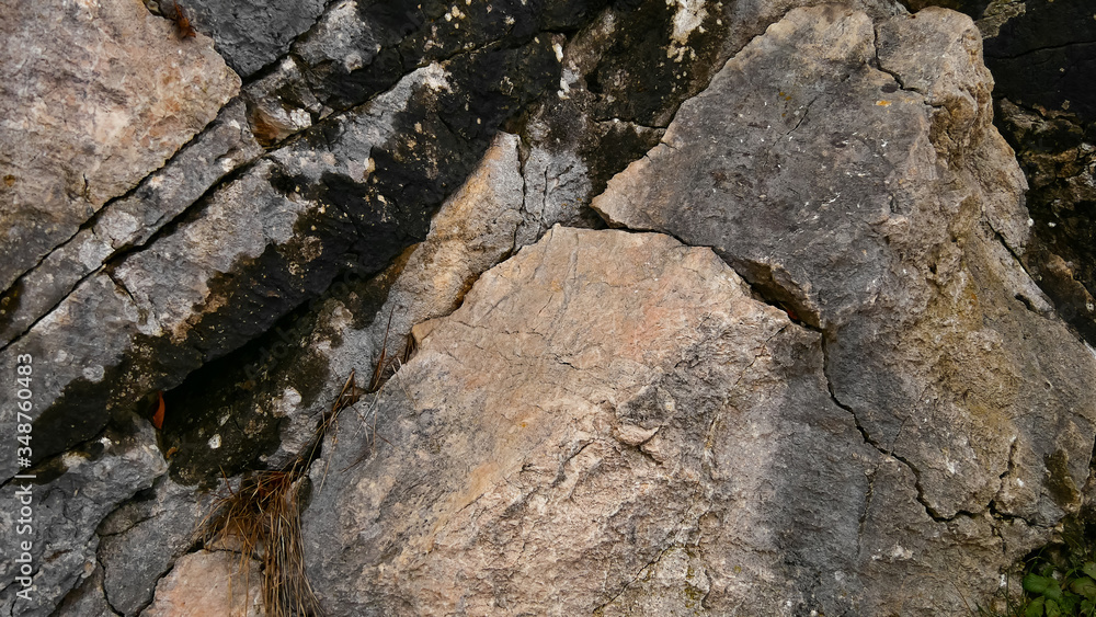 The texture of the mountains. Igneous rocks closeup of a fragment of rock with cracks, streaks. The rough surface of a stone that had been lying on the street for a long time. The texture of the mountains. Igneous rocks closeup of a fragment of rock with cracks, streaks. The rough surface of a stone that had been lying on the street for a long time.