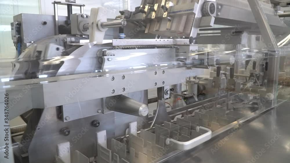 Mass production line moves white pharma pill boxes on automated machine, dolly Mass production line moves white pharma pill boxes on automated machine, dolly