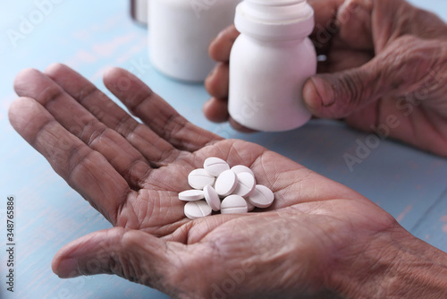 Elderly woman pouring pills from bottle on hand with copy space 