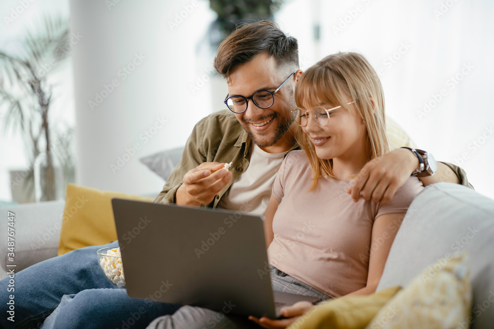 Young couple watching movie on lap top. Loving couple enjoying at home.