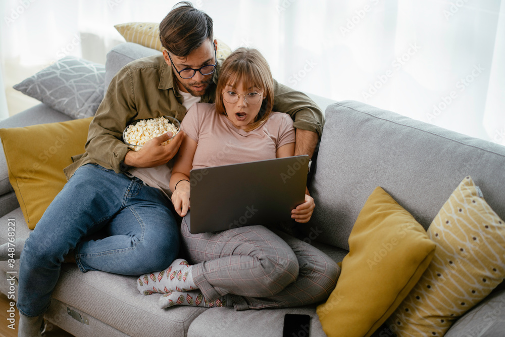 Young couple watching movie on lap top. Loving couple enjoying at home.