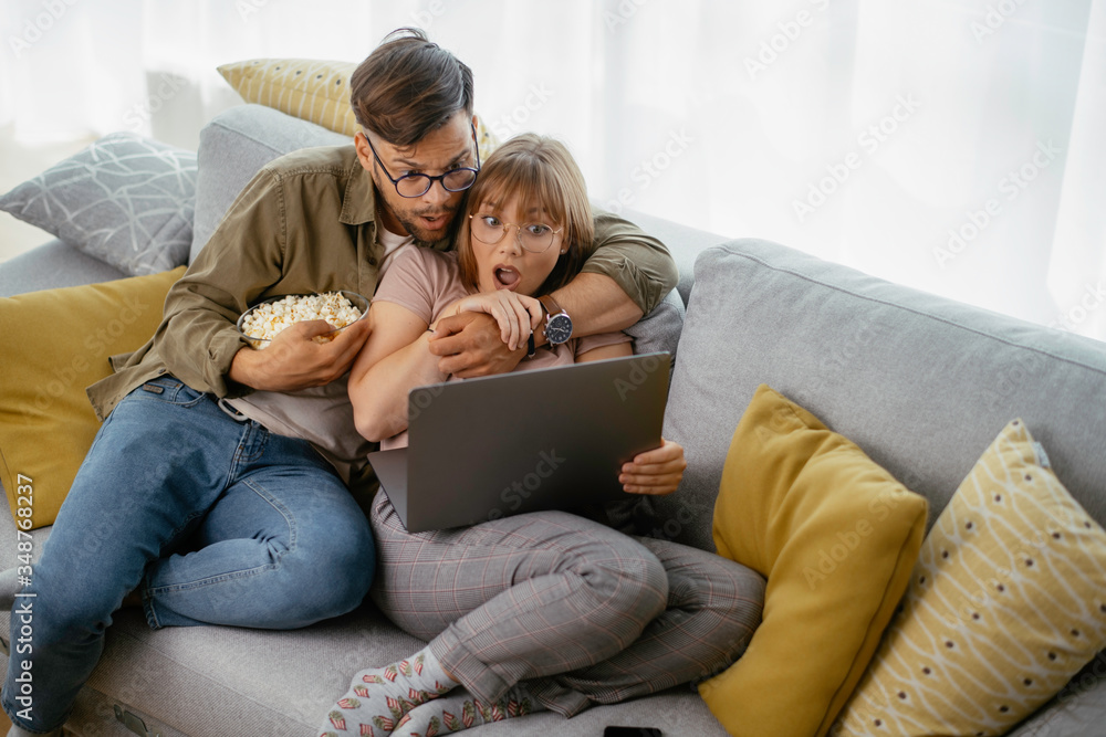 Young couple watching movie on lap top. Loving couple enjoying at home. Young couple watching movie on lap top. Loving couple enjoying at home.