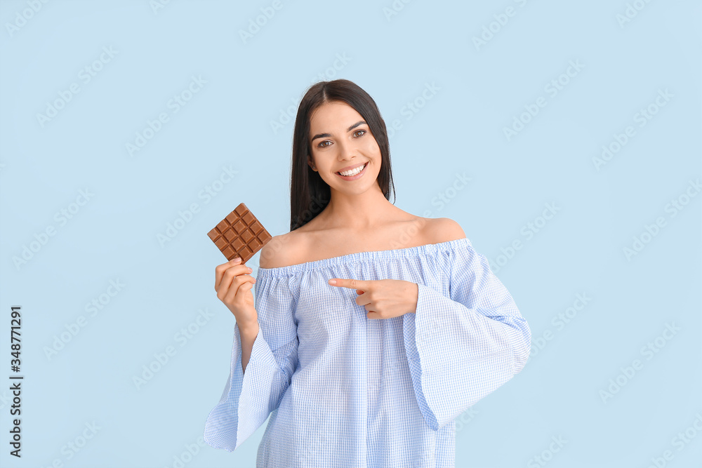 Beautiful young woman with tasty chocolate on color background Beautiful young woman with tasty chocolate on color background