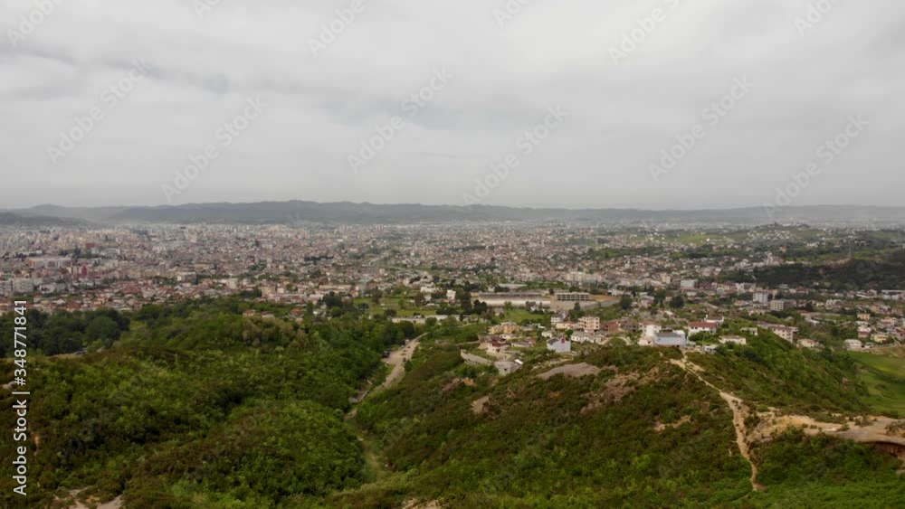 City buildings seen from green hills with lush vegetation on a cloudy day in Tirana, Albania City buildings seen from green hills with lush vegetation on a cloudy day in Tirana, Albania