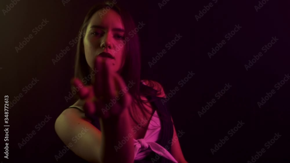 Caucasian girl model dancer dancing on a black background in a nightclub. The brunette on whom the multi-colored light shines, slow motion Caucasian girl model dancer dancing on a black background in a nightclub. The brunette on whom the multi-colored light shines, slow motion