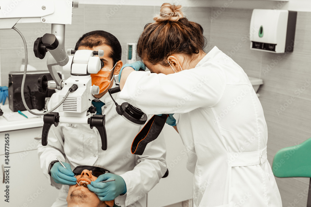 Fototapeta premium Two dentists treat a patient. Professional uniform and equipment of a dentist. Healthcare Equipping a doctor’s workplace. Dentistry