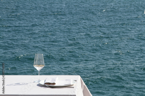 calice di vino bianco su di un tavolo imbandito in che si affaccia sul mare photo