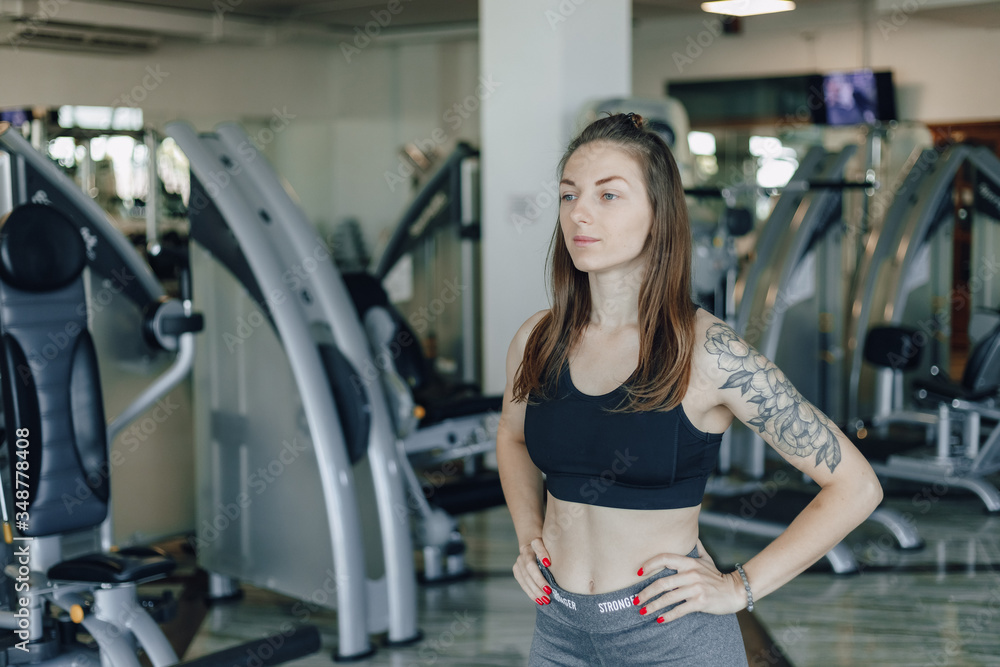 Attractive athletic girl stands on the background of simulators in the gym. healthy lifestyle. Attractive athletic girl stands on the background of simulators in the gym. healthy lifestyle.