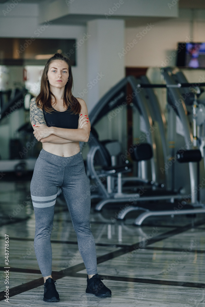 Attractive athletic girl stands on the background of simulators in the gym. healthy lifestyle. Attractive athletic girl stands on the background of simulators in the gym. healthy lifestyle.