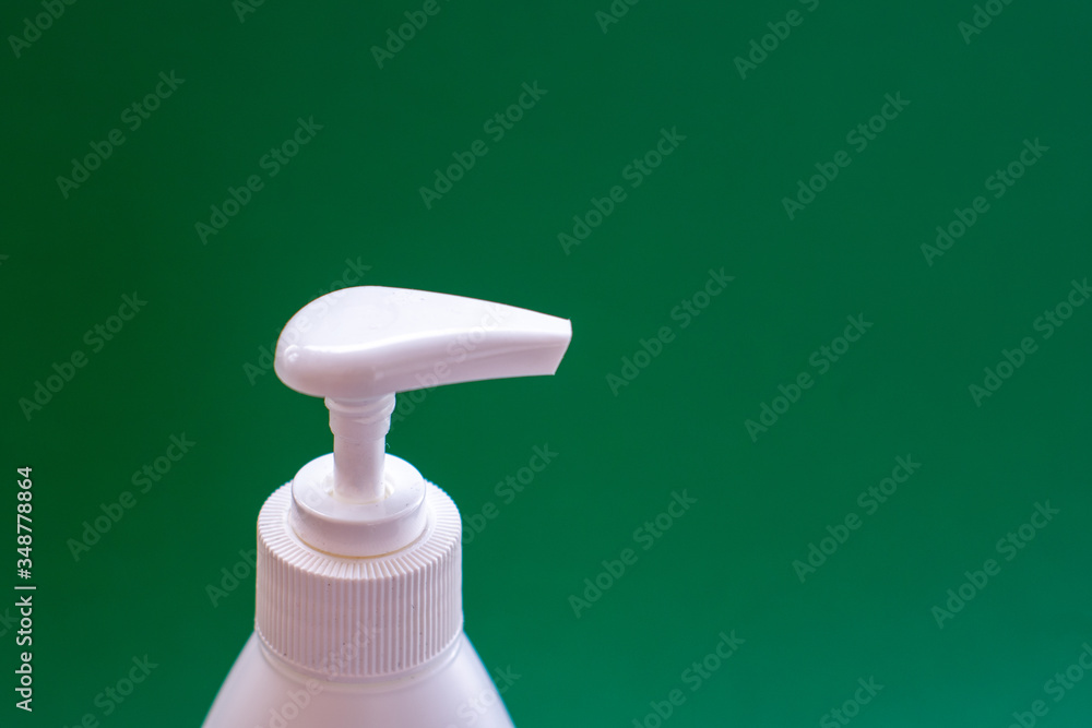 Hygiene and hand protection against viruses and bacteria with soap. Plastic white container with liquid antibacterial soap with a white dispenser closeup on a green background Hygiene and hand protection against viruses and bacteria with soap. Plastic white container with liquid antibacterial soap with a white dispenser closeup on a green background
