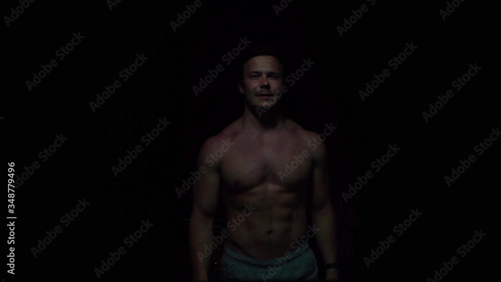 a pumped-up man appears in the frame on a black background without a T-shirt a pumped-up man appears in the frame on a black background without a T-shirt