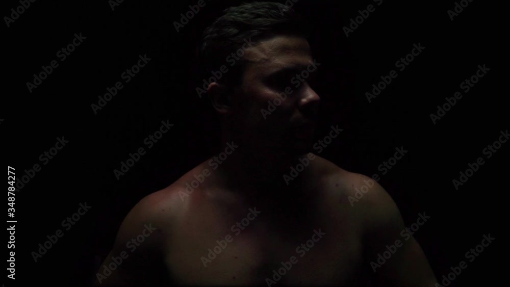 a pumped-up man looks around on a black background without a T-shirt a pumped-up man looks around on a black background without a T-shirt