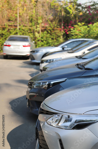 Closeup of front side of soft blue car and other cars parking in outdoor parking lot in sunny day. Vertical view.