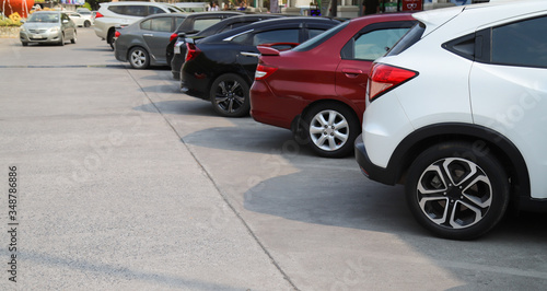 Closeup of rear, back side of white car with other cars parking in outdoor parking area in sunny day.