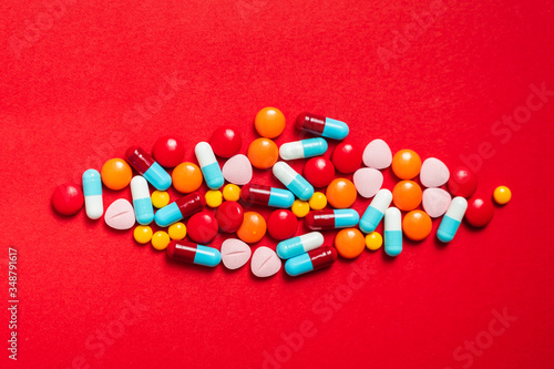 A lot of pill on the red background. Medicine pills, tablets and capsules.