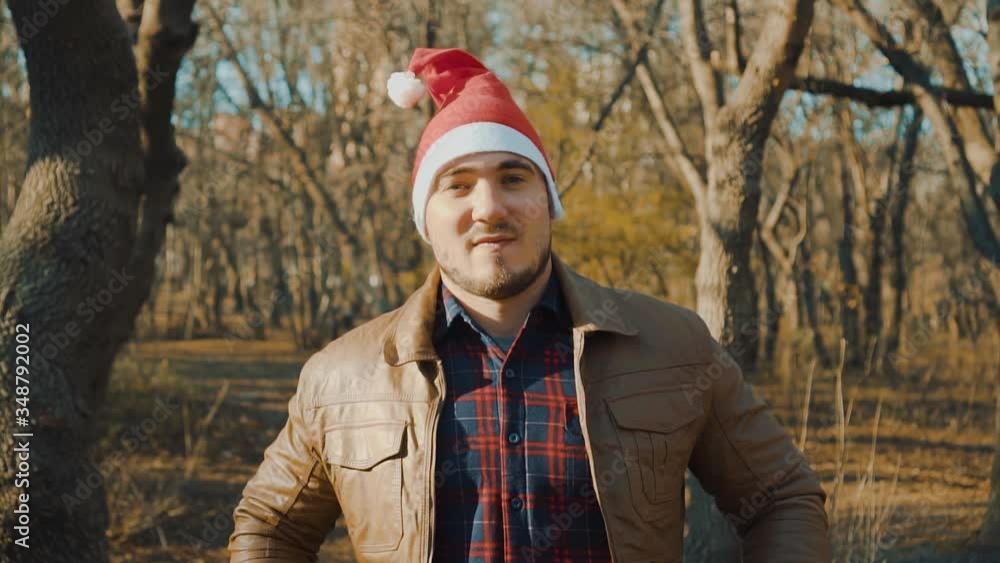 A man in a Santa hat is looking into the frame. Santa Claus straightens his jacket, getting ready to make a speech. A man in a Santa hat is looking into the frame. Santa Claus straightens his jacket, getting ready to make a speech.