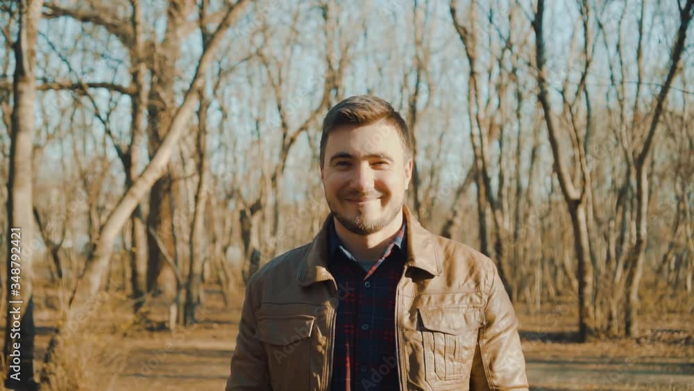 Portrait of a guy in a leather jacket on a background of a spring park. A smiling guy is enjoying the upcoming spring, looking at the frame and showing the peace sign. Portrait of a guy in a leather jacket on a background of a spring park. A smiling guy is enjoying the upcoming spring, looking at the frame and showing the peace sign.
