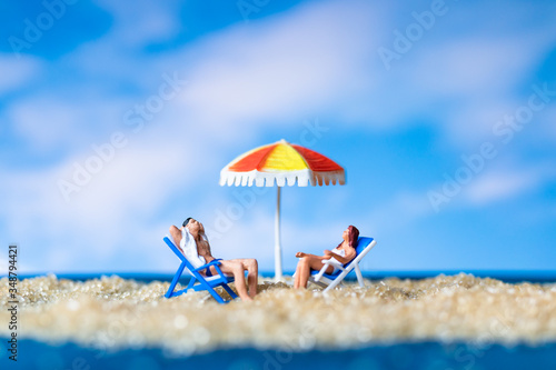 Miniature people sunbathing on The baech with blue sky background , Summer time concept