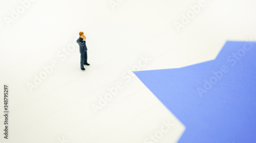 A miniature figure businessman standing and thinking on paper graph background with copy space using for business,marketing and financial concept.