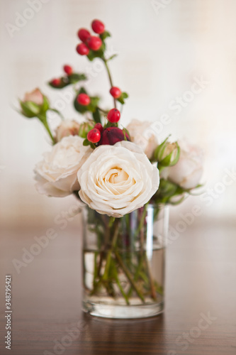 roses and red berries in a glass