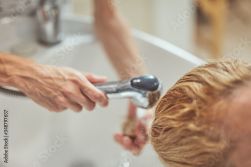 Hair dresser washing hair to a customer in the salon.