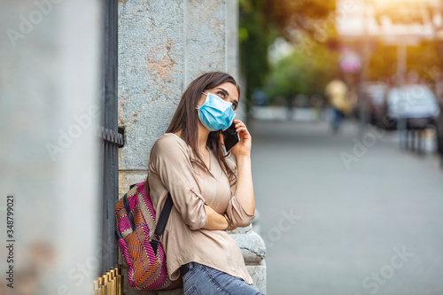 Portrait of young woman on the street wearing face protective mask to prevent Coronavirus and anti-smog and using smartphone. Young Woman With Face Mask Talking On The Phone