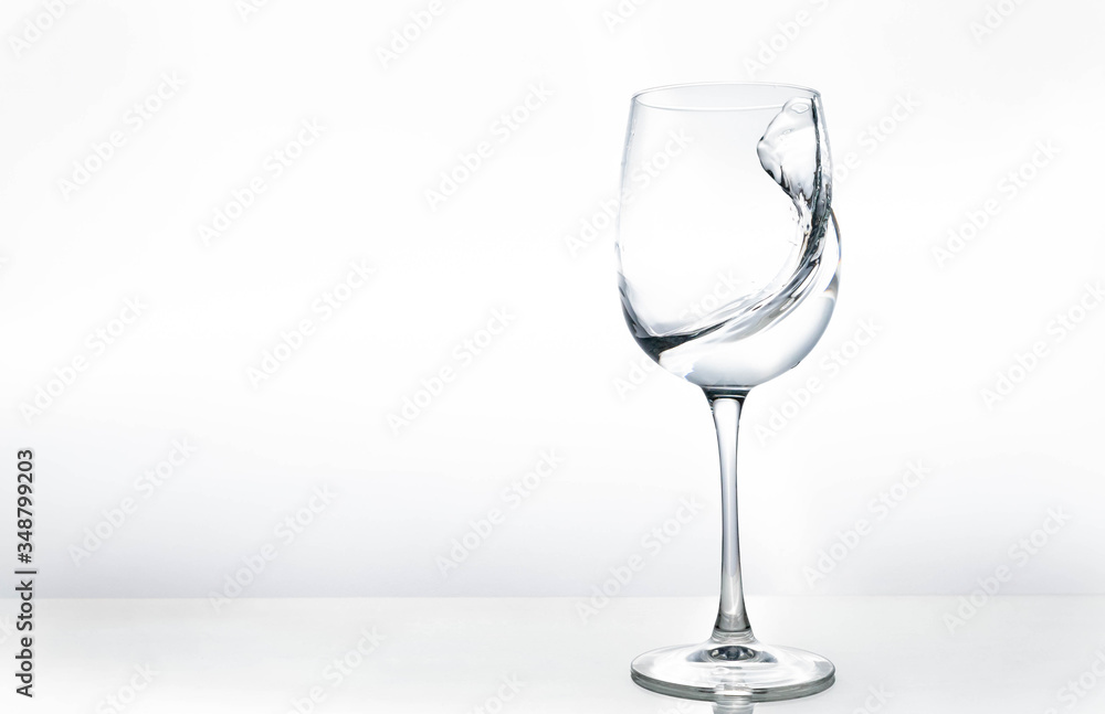 Water in a wine glass. Splash of liquid on a white background. Isolated object. Spray.