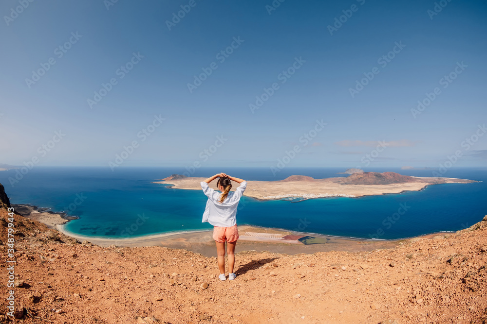Viewpoint to La Graciosa from Lanzarote and happy traveller woman. View of La Graciosa Island and blue ocean Viewpoint to La Graciosa from Lanzarote and happy traveller woman. View of La Graciosa Island and blue ocean