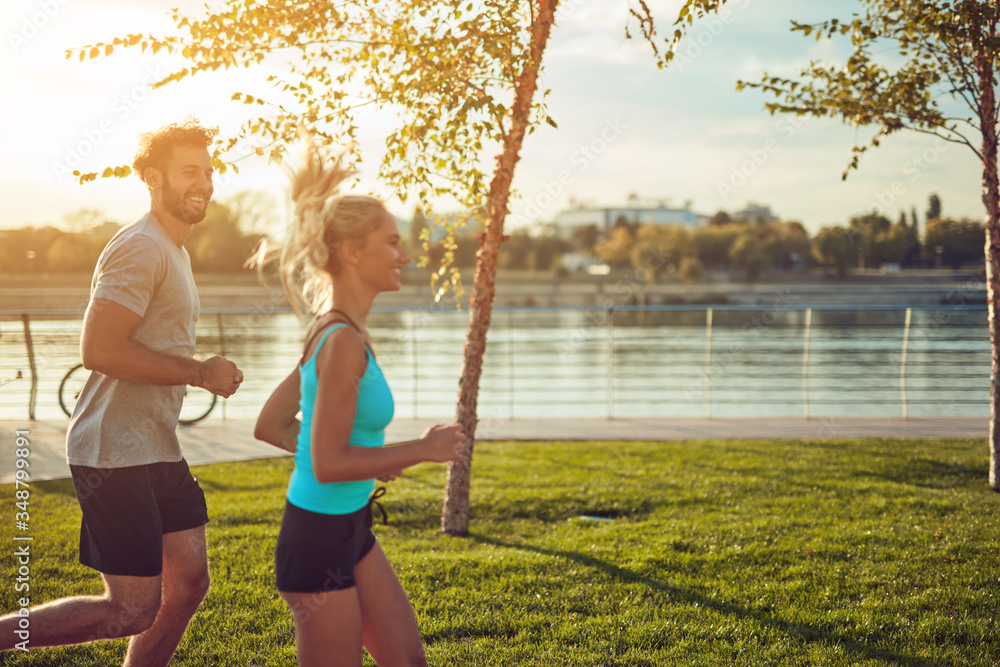 Fototapeta premium Nowoczesna kobieta i mężczyzna jogging / ćwiczenia w środowisku miejskim w pobliżu rzeki.