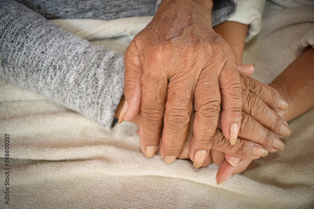 Close up granddaughter takes care of the health sick grandmother at home by holding hands. Lifestyle support the love of the family. Close up granddaughter takes care of the health sick grandmother at home by holding hands. Lifestyle support the love of the family.