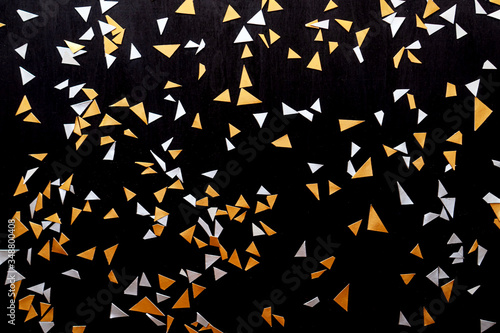 Golden silver confetti isolated on black background.