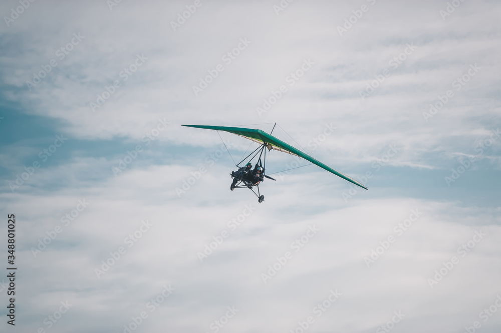 The motorized hang glider in the blue sky.