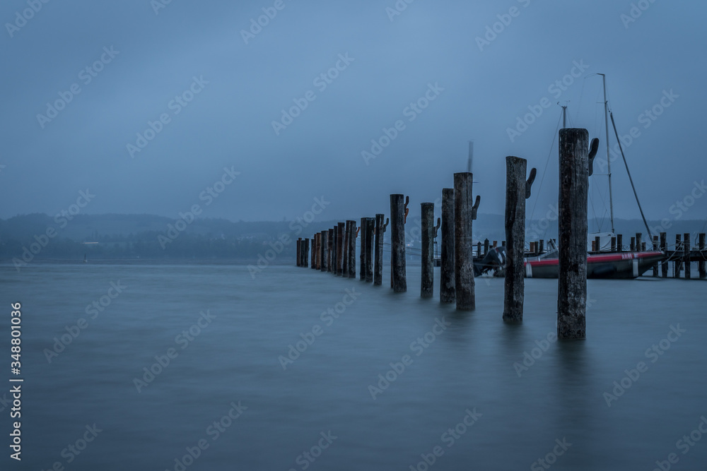 Long exposure of the water at ammersee in Germany with wooden pillars in the foreground