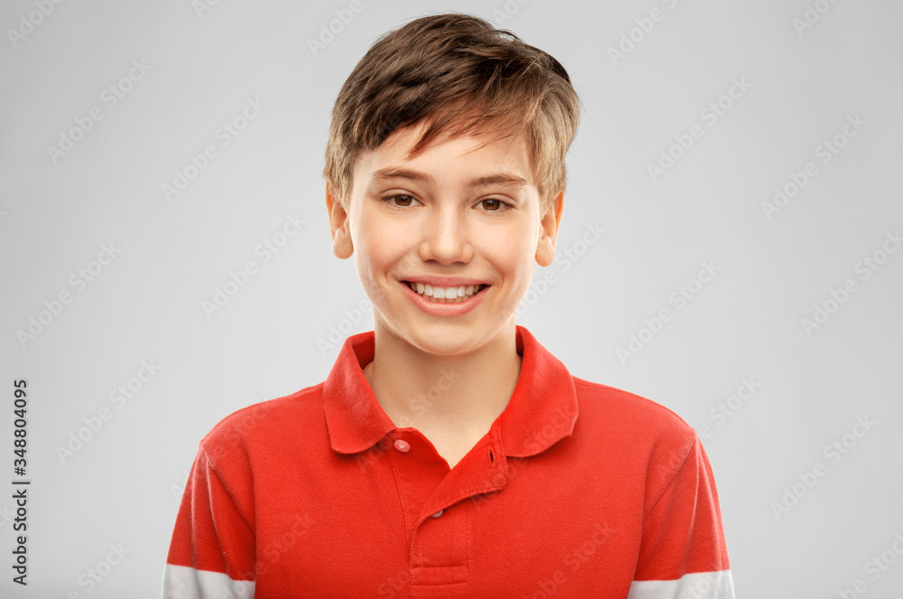 childhood, fashion and people concept - portrait of happy smiling boy in red polo t-shirt over grey background childhood, fashion and people concept - portrait of happy smiling boy in red polo t-shirt over grey background