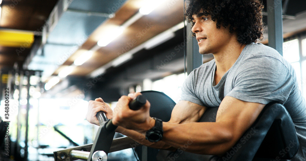 Muscular man working out in gym doing exercises with dumbbells at biceps Muscular man working out in gym doing exercises with dumbbells at biceps